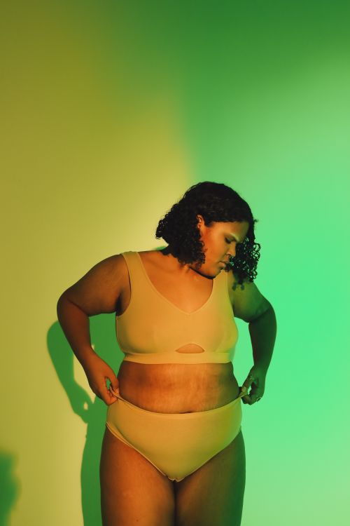Free Empowering portrait of a plus-size woman embracing body positivity in a green-lit studio. Stock Photo