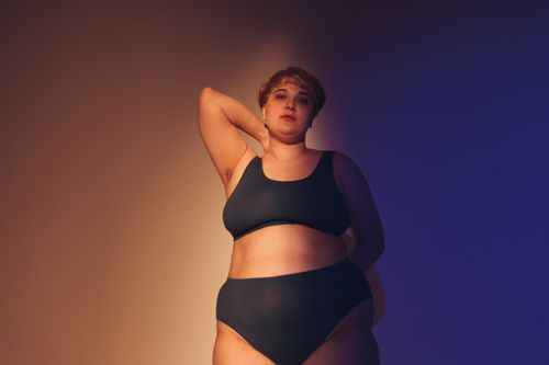 Free Confident plus size woman embraces body positivity in a studio setting with artistic lighting. Stock Photo