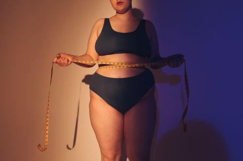 Free Confident plus size woman in studio holding a tape measure, emphasizing body positivity. Stock Photo