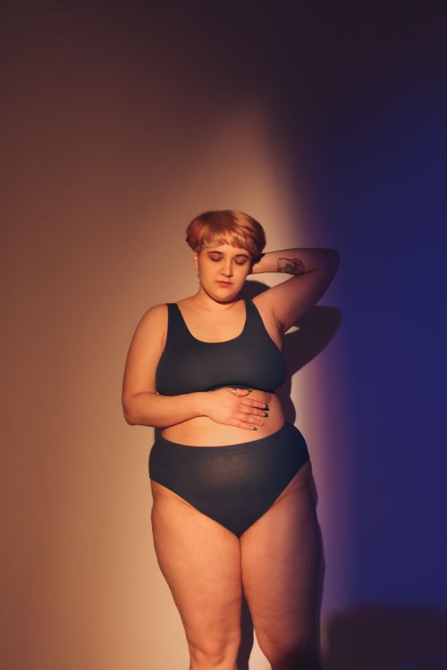 Free Empowered plus-size woman in a tank top posing confidently in a studio setting. Stock Photo