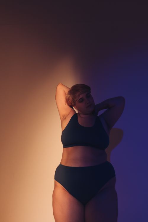 Free Confident plus size model posing in studio with dynamic lighting for body positivity. Stock Photo