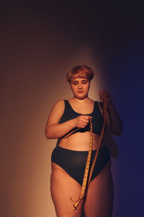 Free Empowering studio portrait of a body-positive woman in underwear, holding a tape measure. Stock Photo