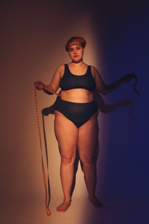 Free Body positive woman in underwear holding a tape measure in a studio setting. Stock Photo