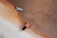 Aerial view of old boats placed on wet sandy coast of sea on island