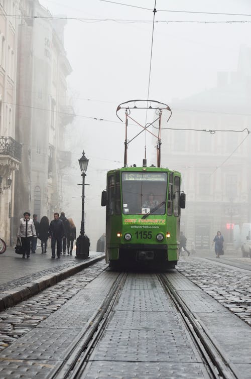 A Green Tram in a Foggy Urban Area