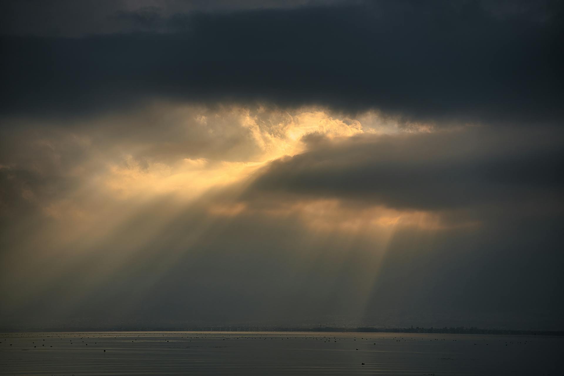 Captivating sunset rays breaking through clouds over serene Erhai Lake in Dali, China.