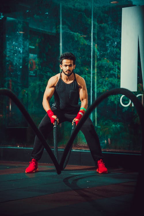 A Man Using Battle Ropes at a Gym