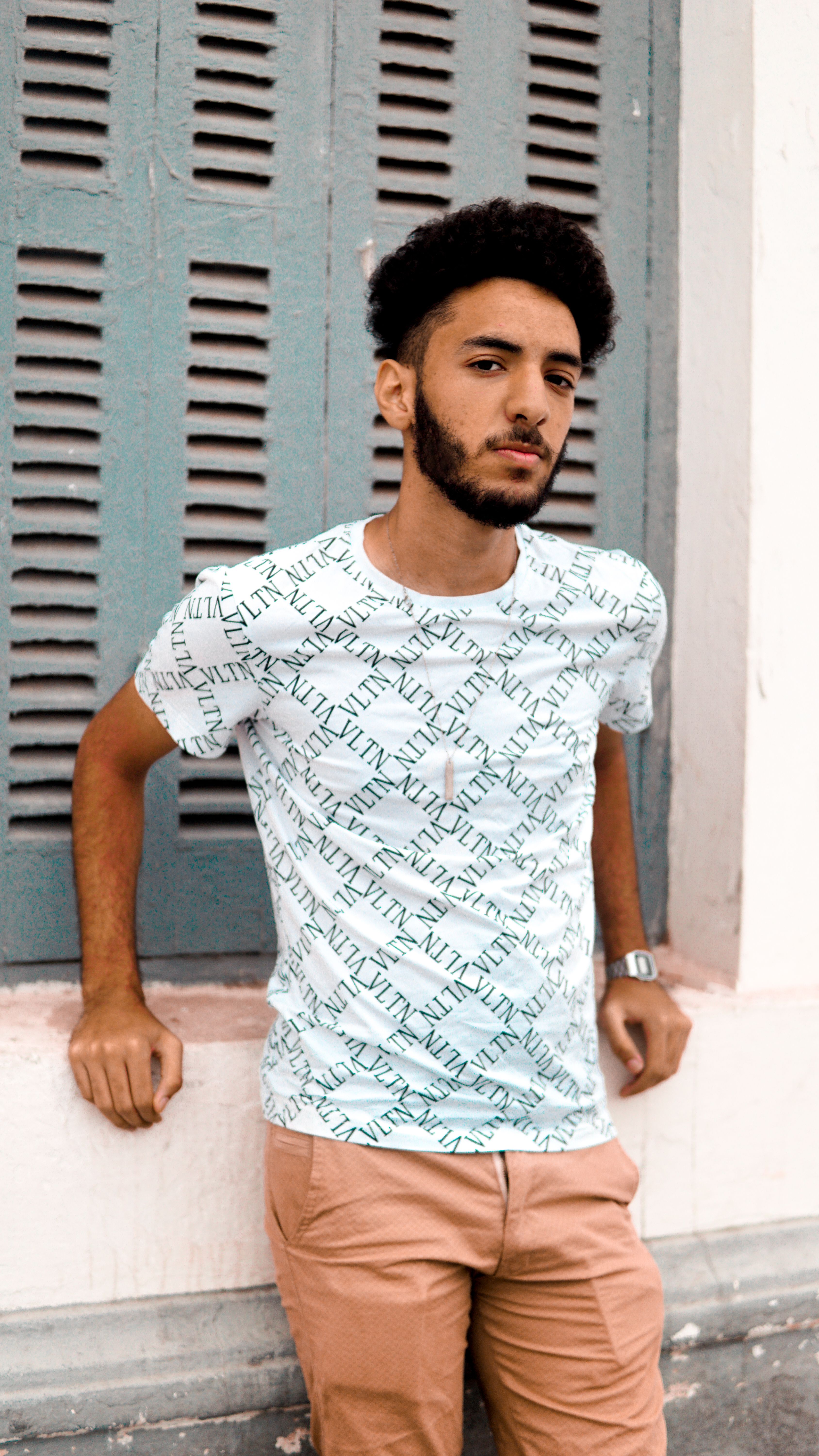 Stylish young man in casual attire posing against urban backdrop in El Jadida, Morocco.