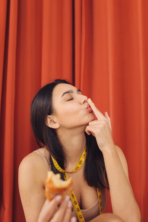 A Woman with Tape Measure on Her Neck Eating Bread