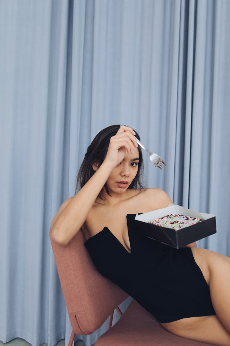 Photograph Of A Woman Eating Cake While Sitting