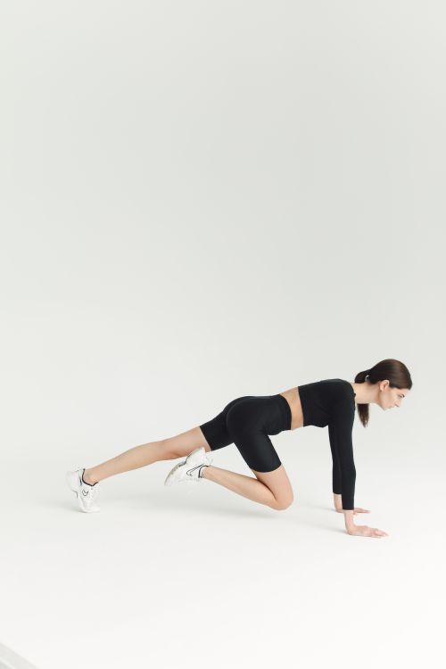 Free Side view of a woman doing fitness exercises in a minimalist studio setting with ample copy space. Stock Photo