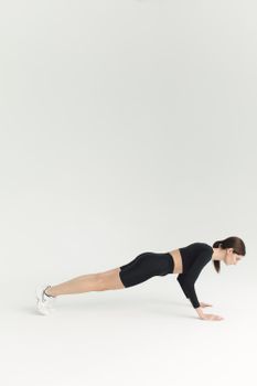 A woman in activewear doing push-ups on a white background.