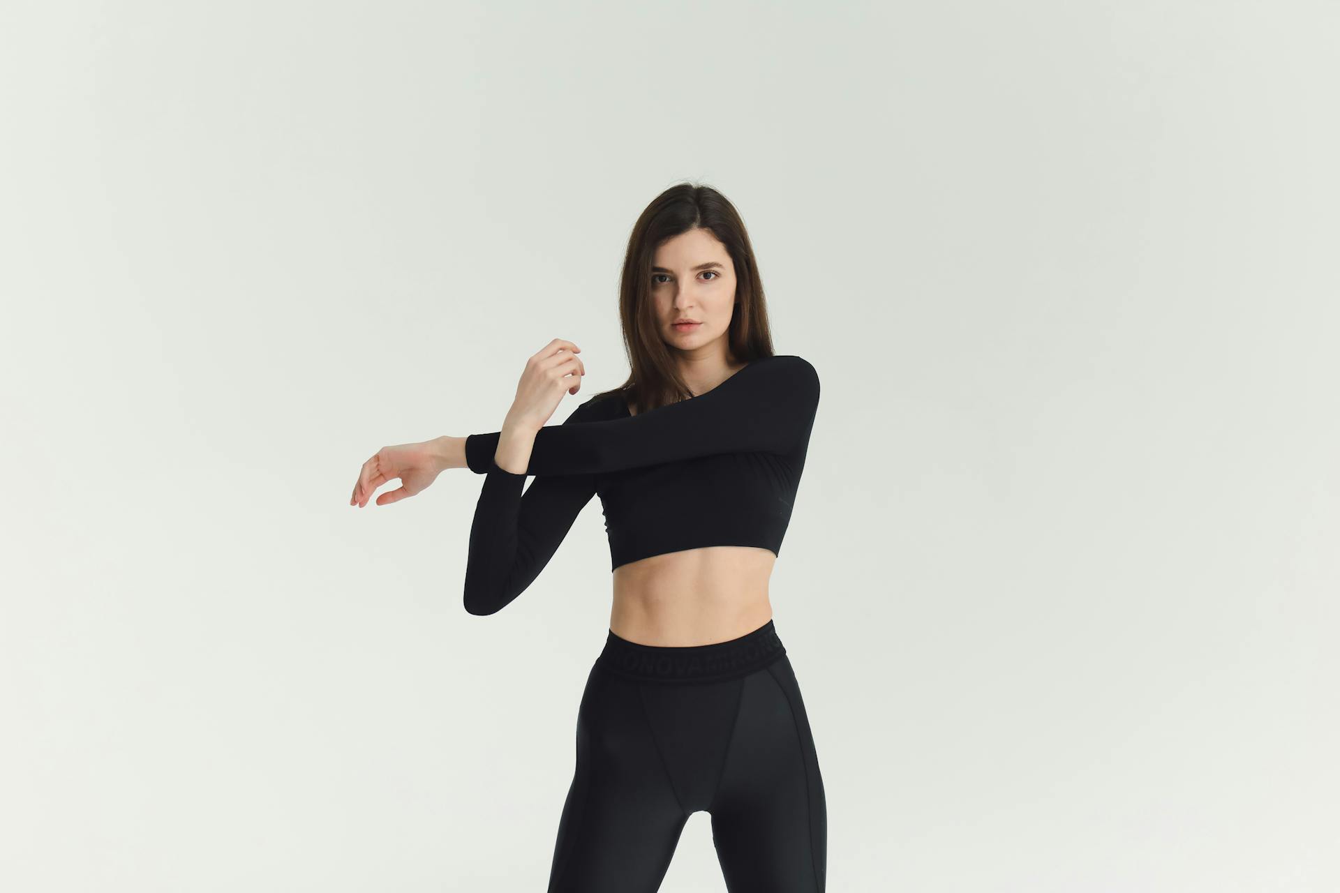 Woman in black activewear stretching indoors, showcasing a fitness lifestyle.