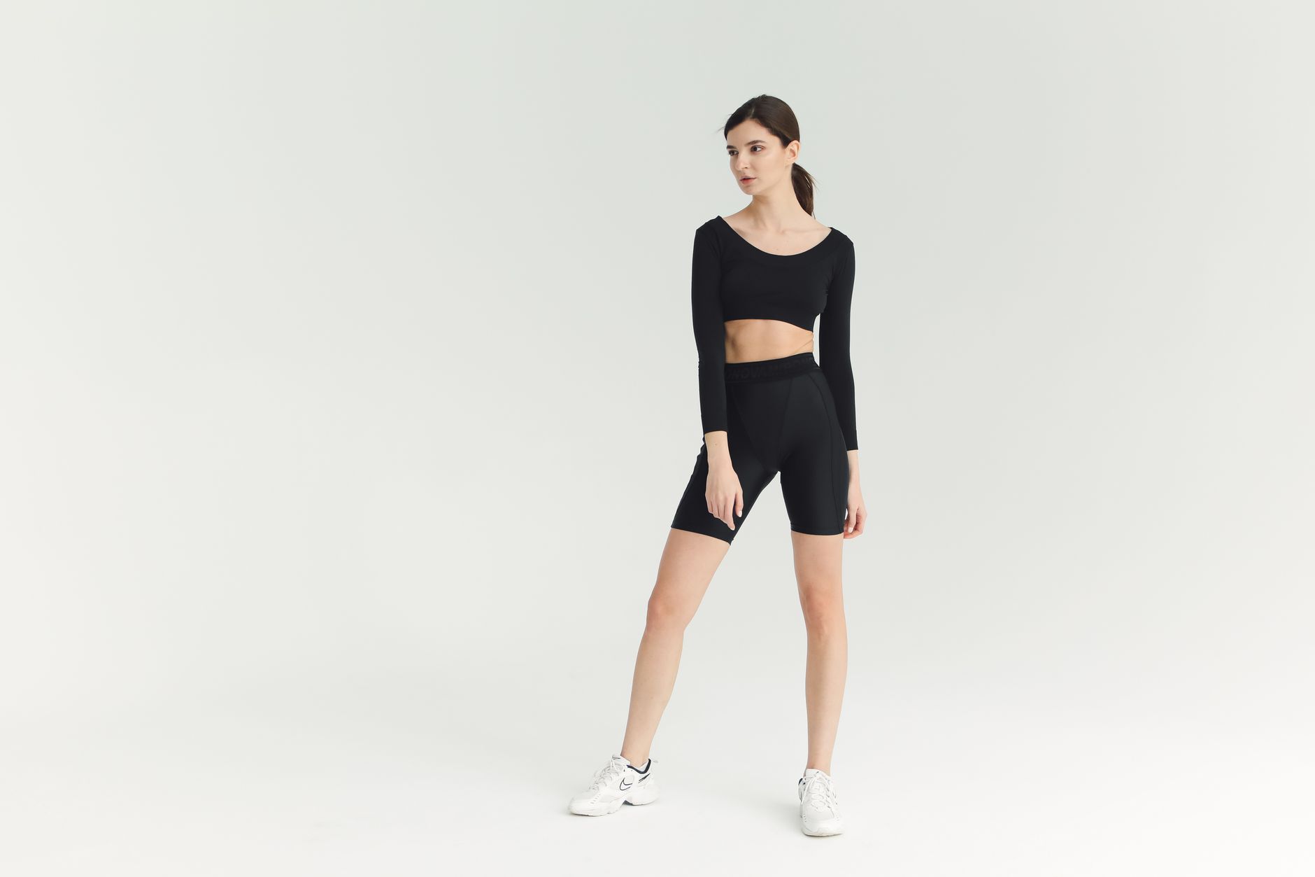 A sporty young woman poses confidently in stylish fitness attire, showcasing a modern activewear look.