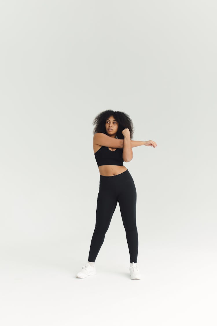 A Curly Haired Woman Stretching Her Arms 