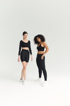 Two women in stylish activewear pose confidently in a minimal studio setting.