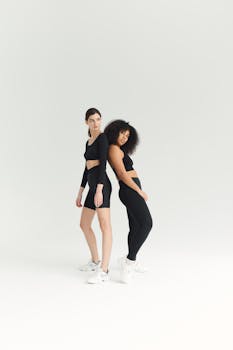 Two women posing back-to-back in activewear on a white background.