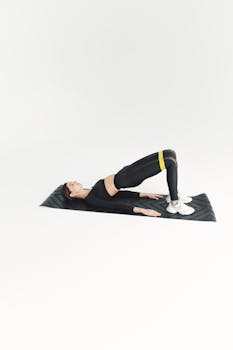 Woman doing fitness workout on mat with resistance band in studio setting.