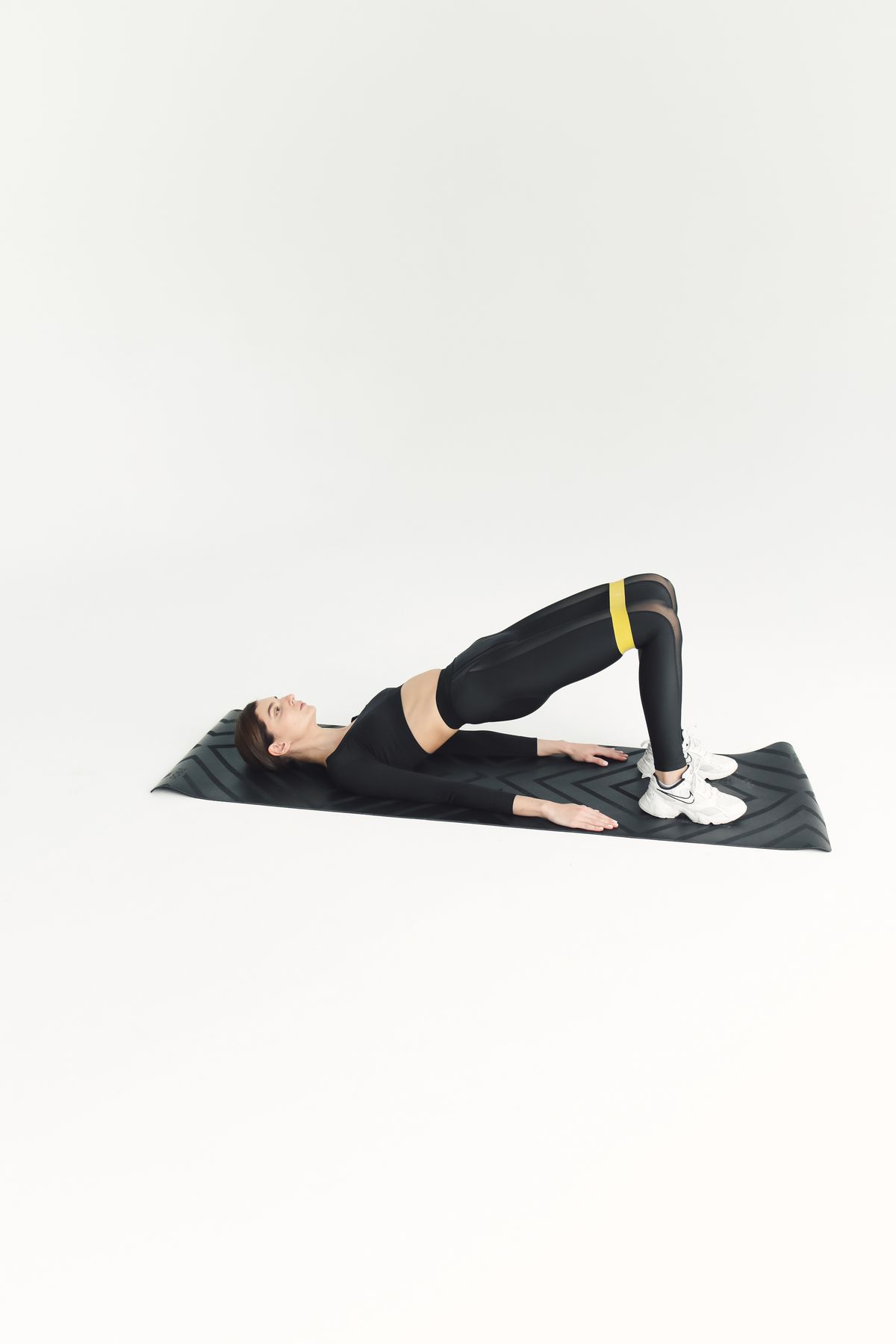 Mulher fazendo ponte de glúteos em tapete de exercícios