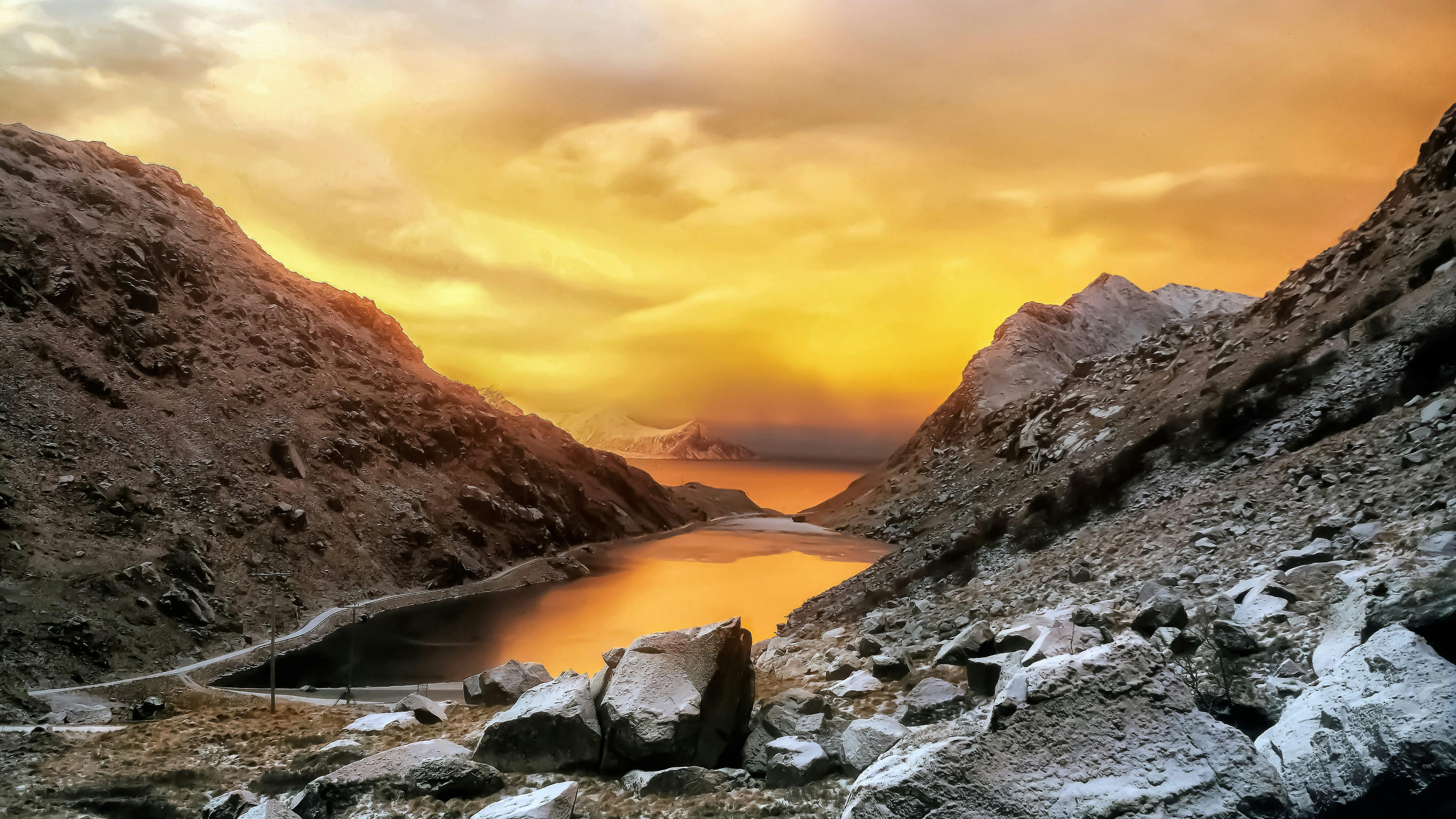 Stunning golden sunset over a serene lake in Nordland, Norway with rugged mountains.