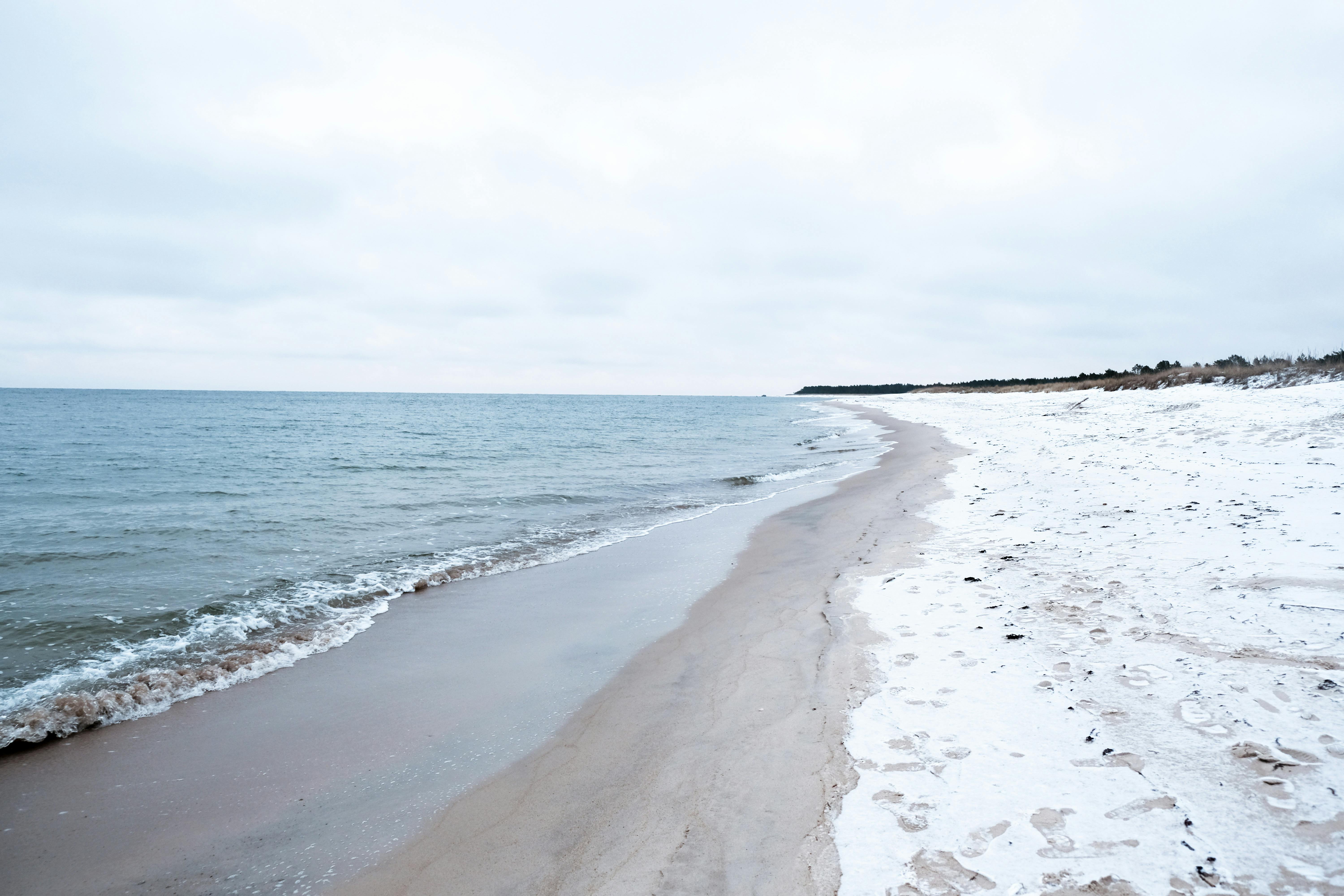 A tranquil snowy beach in Estonia, showcasing a serene coastal winter landscape.