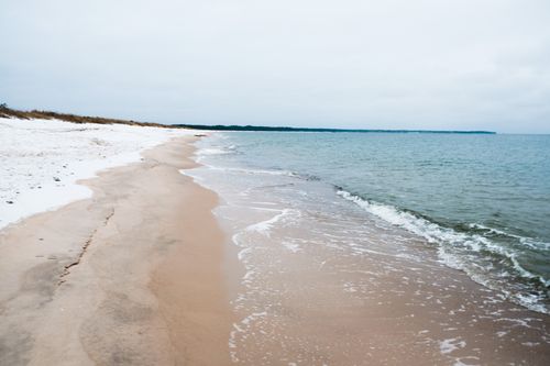 Free A tranquil winter beach scene with gentle waves lapping at the sandy shoreline. Stock Photo