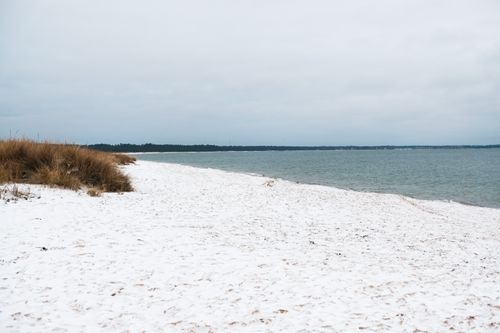 Free A beautiful winter scene of a snowy beach meets the blue sea under a cloudy sky in Estonia. Stock Photo
