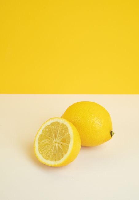 Freshly sliced lemon on a vibrant yellow background, perfect for food and health imagery.