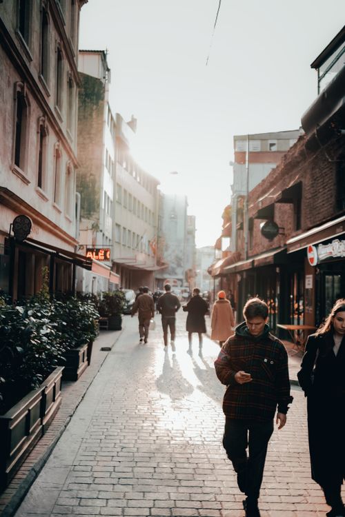 Free A bustling pedestrian street in the city, with people walking and sunlight casting shadows. Stock Photo