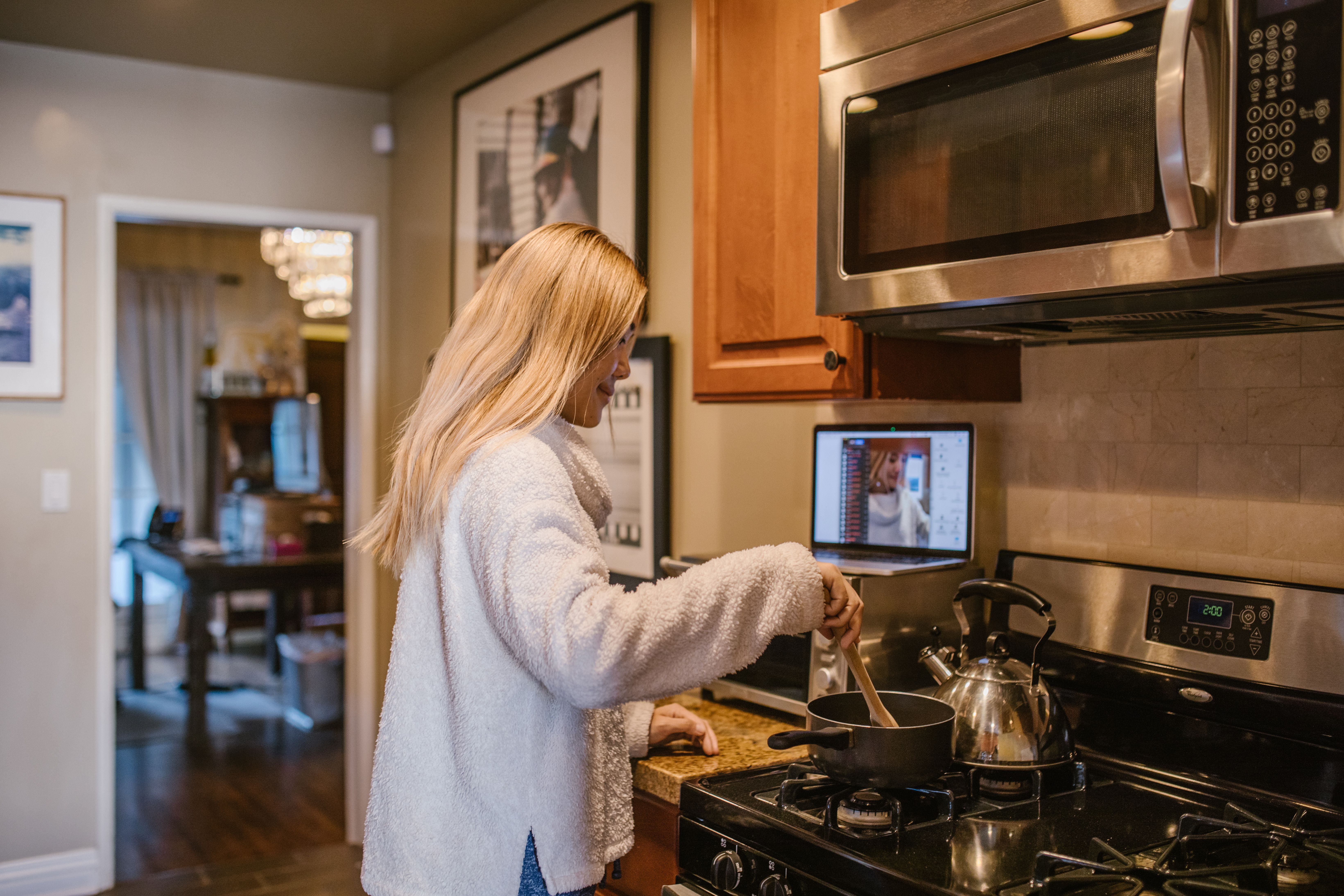 Adult woman learning online from home while managing household activities
