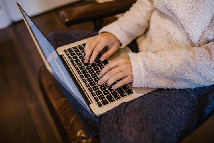 Person Wearing Fleece Sweater Typing On A Laptop 