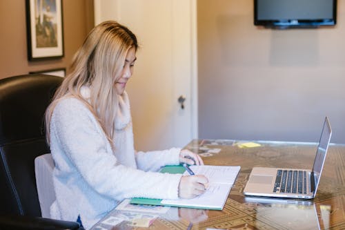 Woman in White Fleece Sweater Sitting at the Table