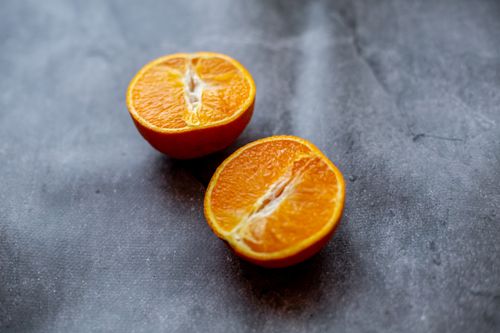 Free From above of fresh ripe juicy oranges cut into halves placed on dark surface in light room in kitchen at home Stock Photo