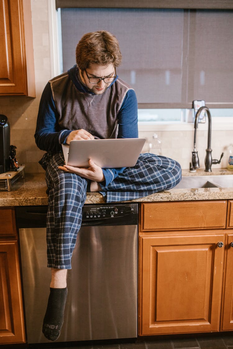 Man Using Laptop While Sitting On Countertop