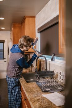 A man in pajamas makes a video call with his laptop in the kitchen.