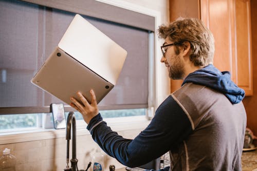 Photograph of a Man Holding His Laptop