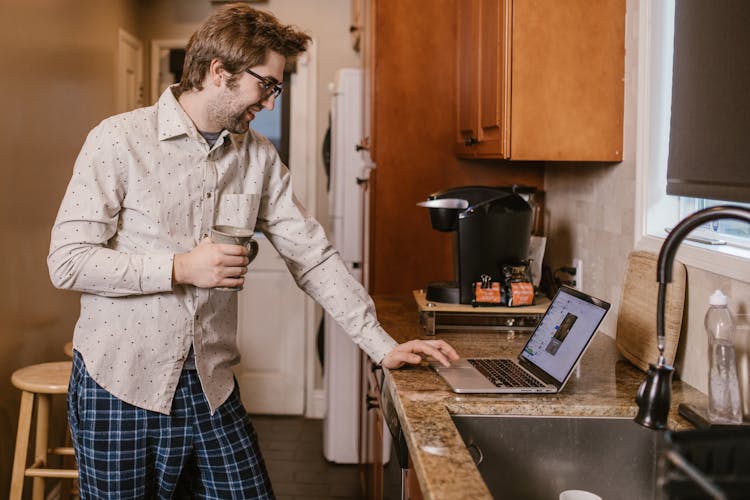 A Man Smiling While Looking At His Laptop