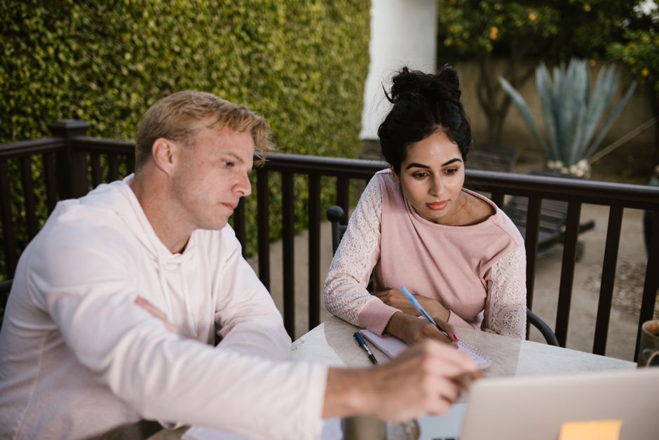 Um homem e uma mulher envolvidos em aprendizado online ao ar livre, colaborando em um laptop.