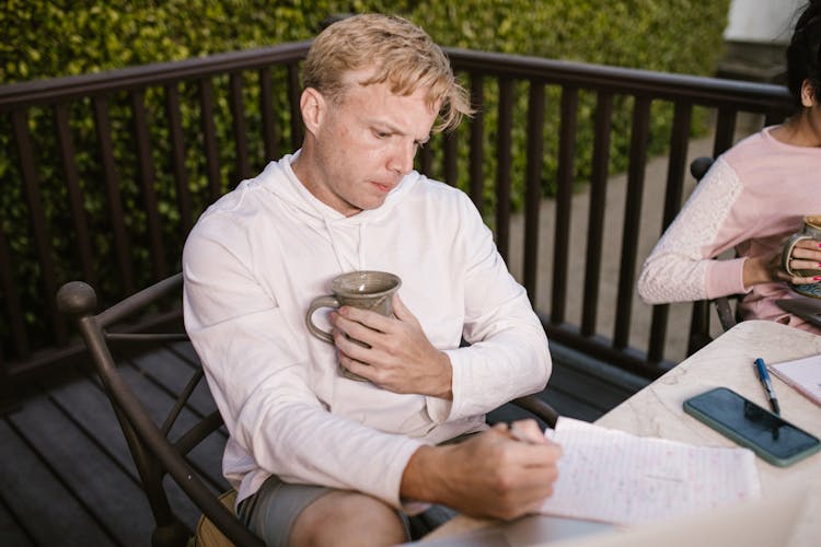 A Man In A White Hoodie Writing