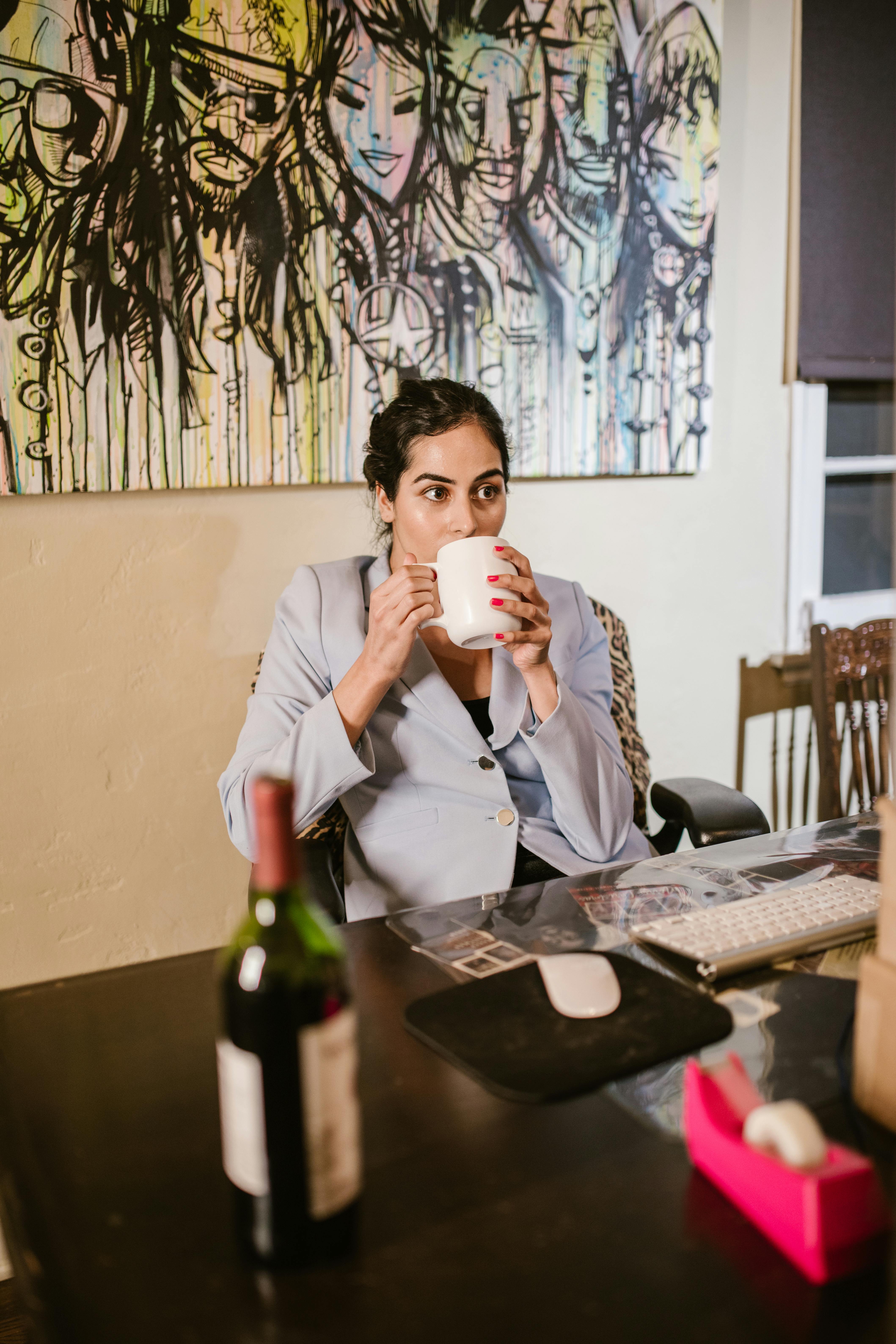 a woman sitting while drinking on a ceramic mug