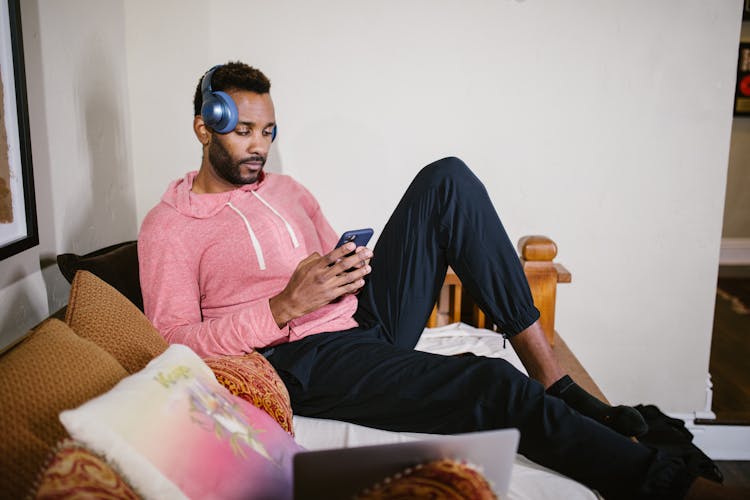 Photo Of A Man With Headphones Using His Cell Phone