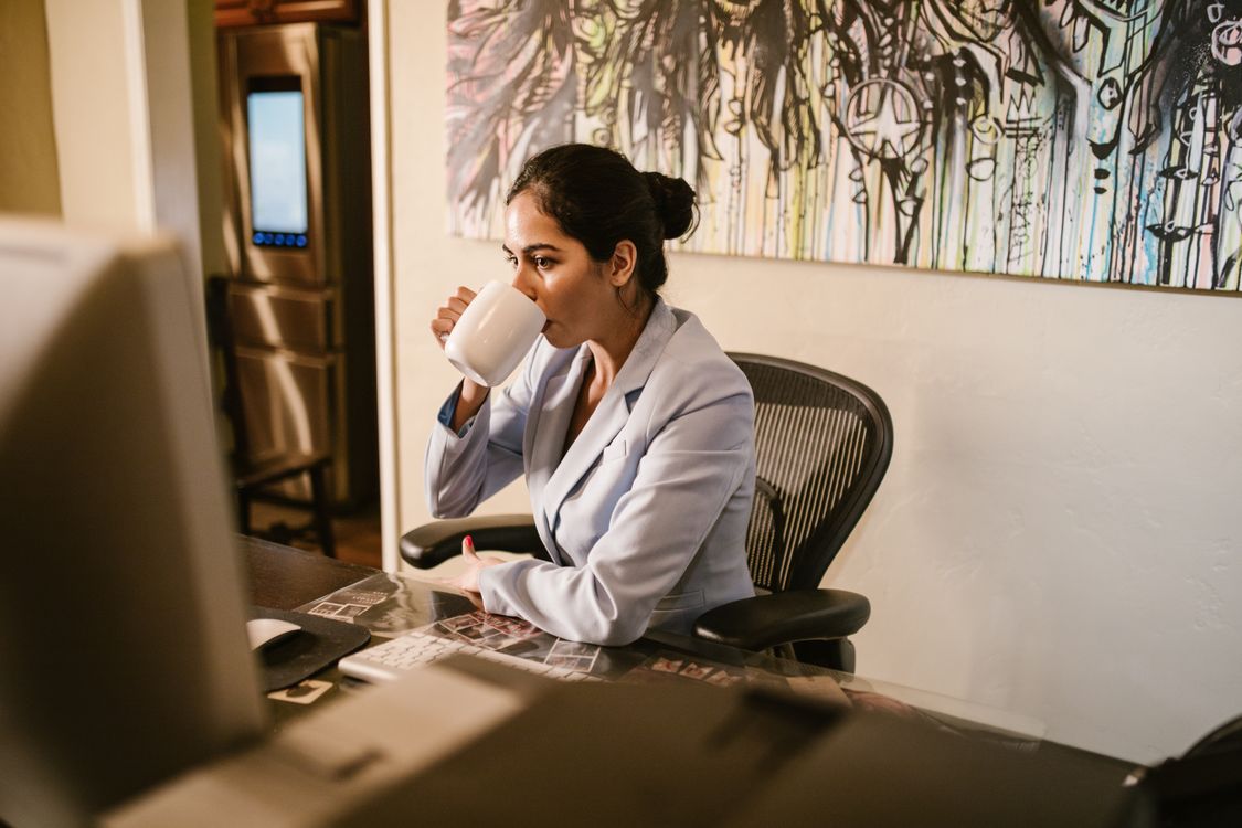 Woman working from home office with laptop and coffee — the real daily life of a digital product creator