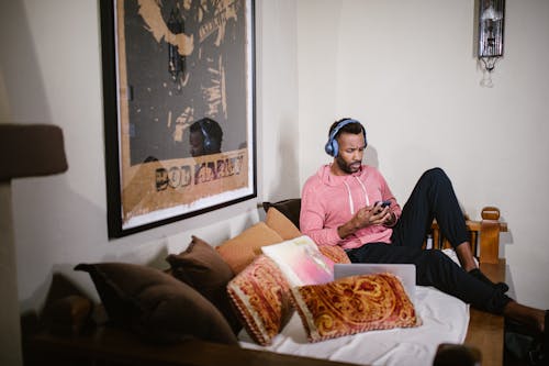 Free A Man in Pink Hoodie Wearing Headset while Using His Mobile Phone Stock Photo