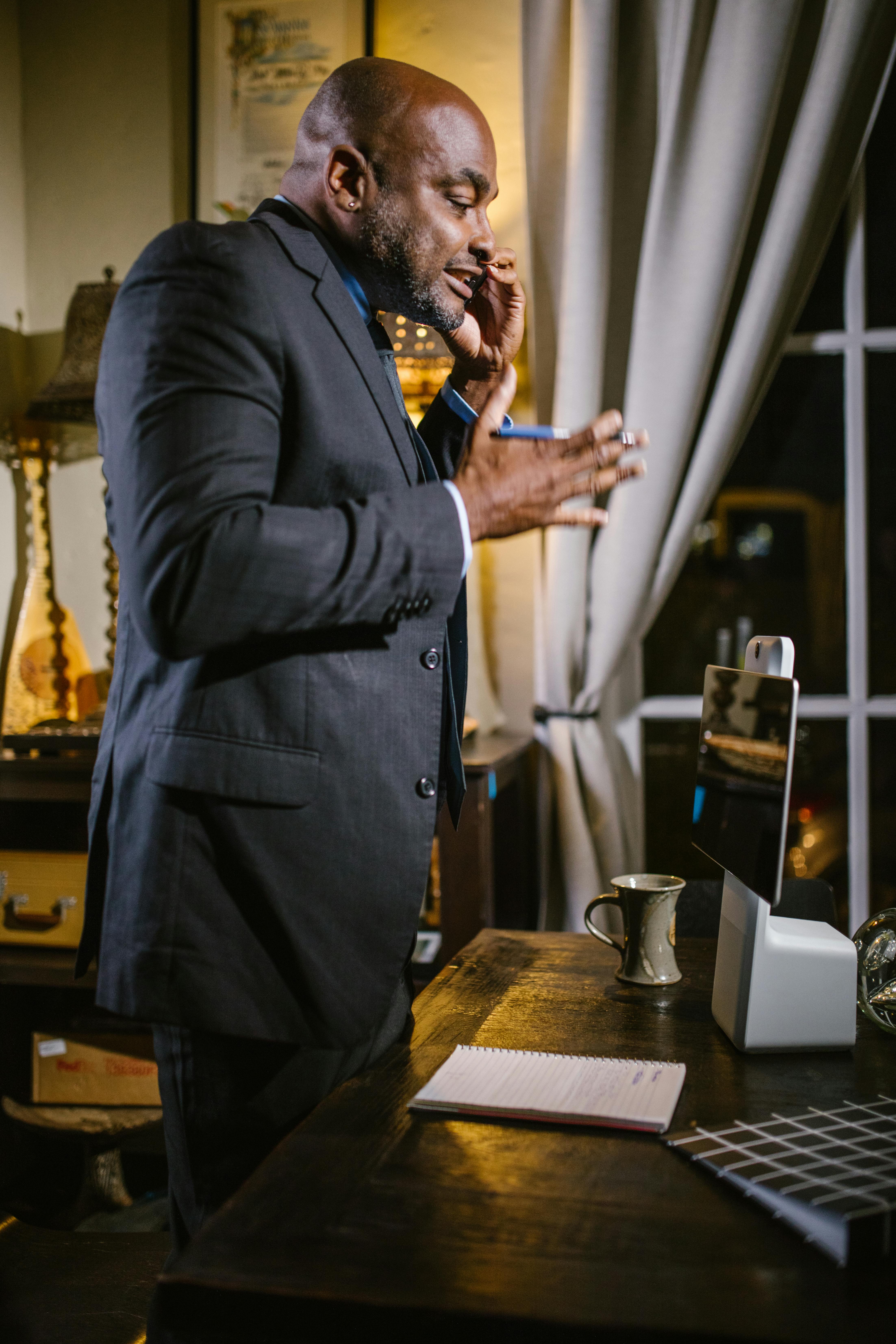 man in black coat standing near brown wooden table