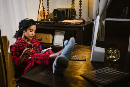 Relaxed woman enjoying a book and wine at home, feet up and comfortable.