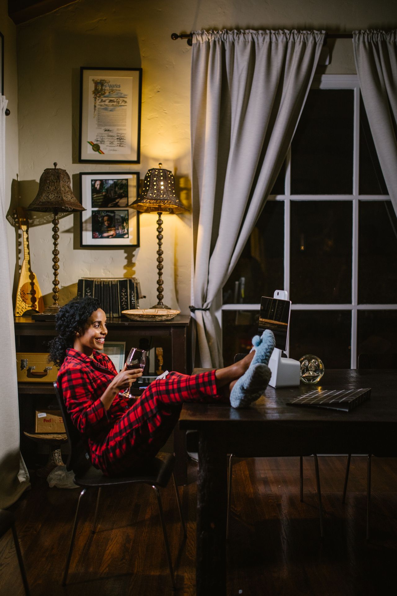 Woman in red plaid pajamas and fuzzy socks with her feet up at a desk