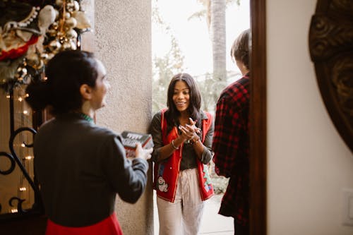 Woman Giving Present to Other Woman in Doorway