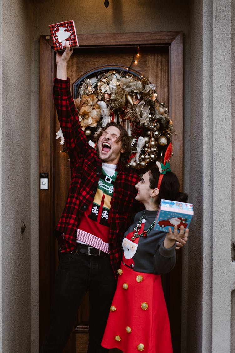 Happy Couple Posing By Door With Christmas Presents In Hands