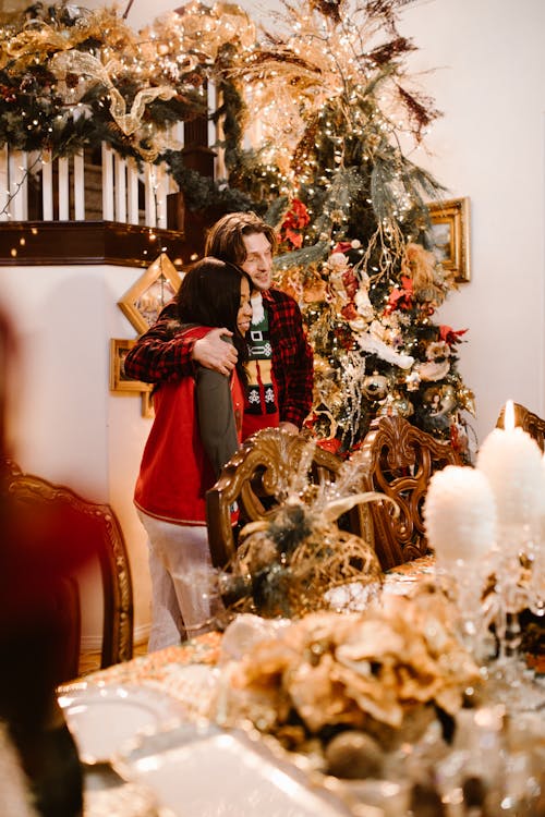 Man and Woman Hugging Each Other Near a Christmas Tree