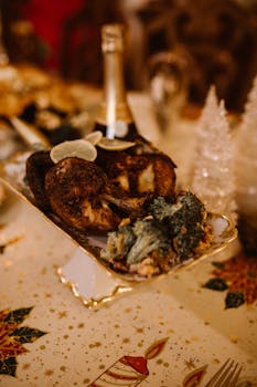 A close-up of a festive Christmas dinner table with roasted meat and decorative elements.